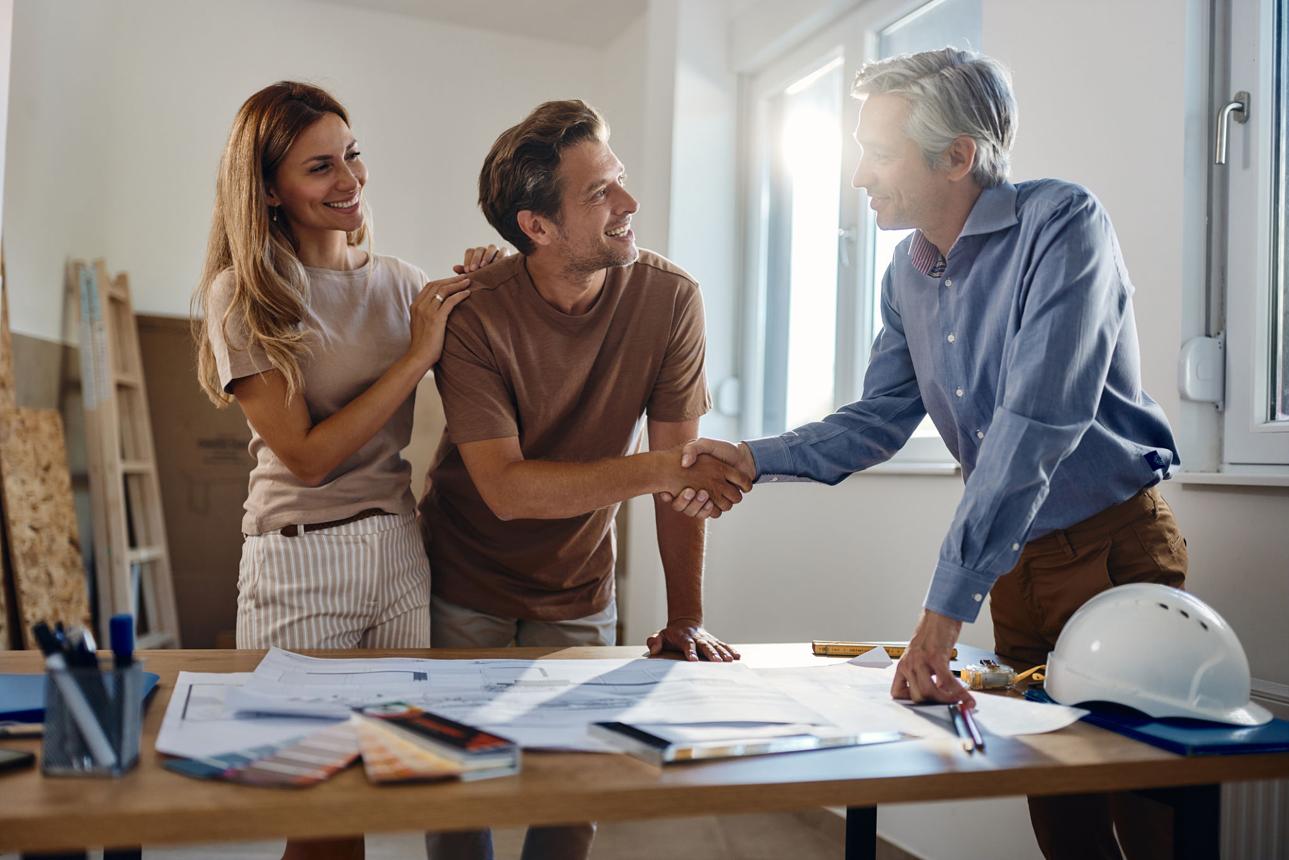 Clients shaking hands with their designer over project drawings