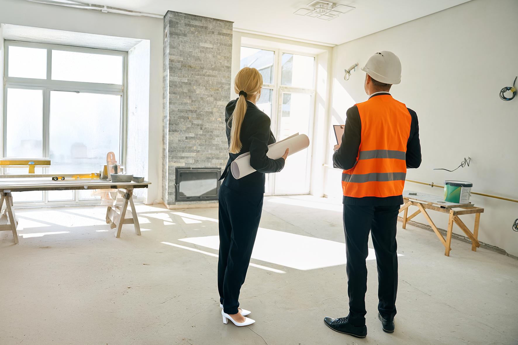 Architect and contractor reviewing an unfinished room during renovation